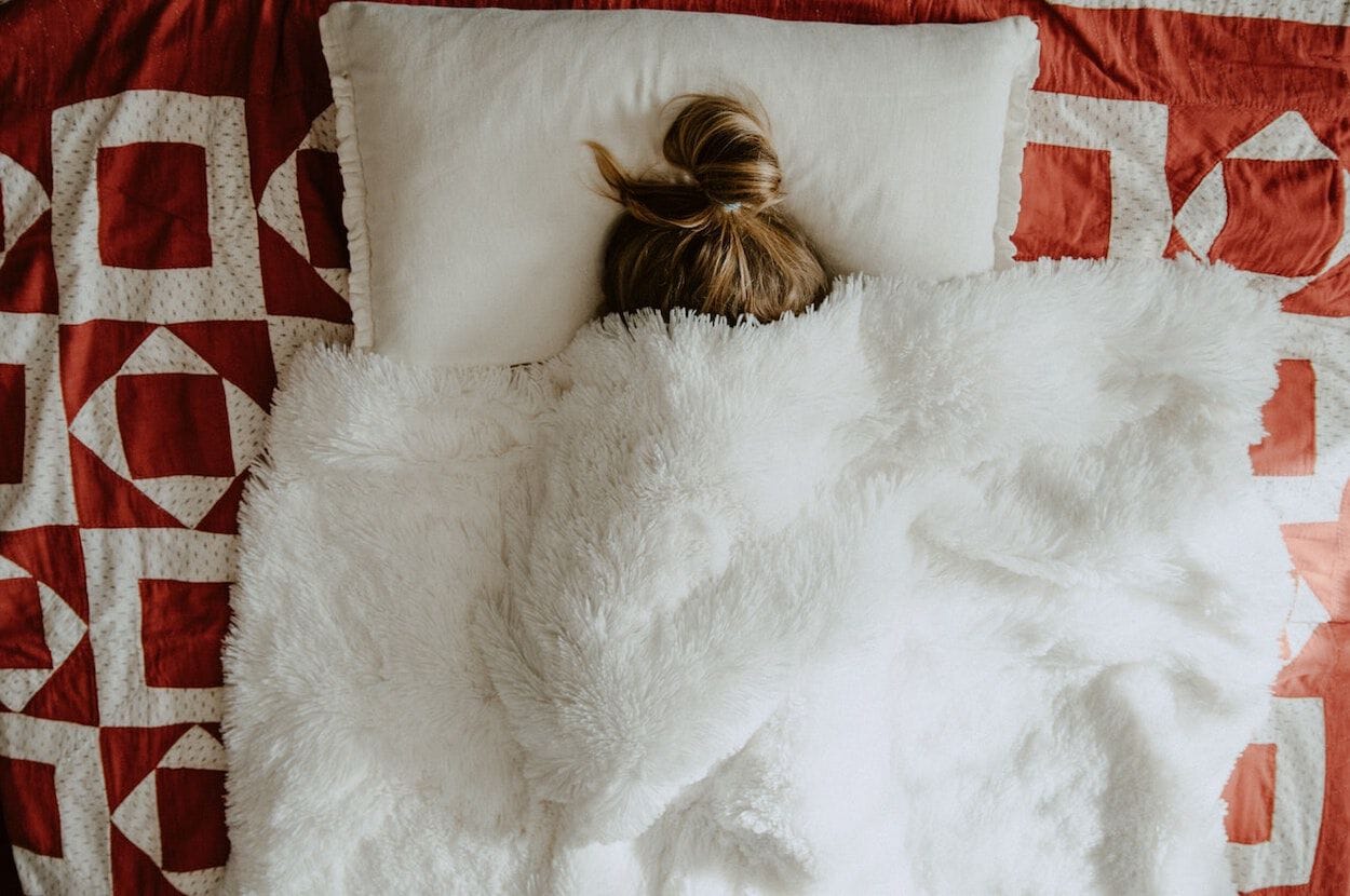 meisje ligt in bed met deken over haar hoofd