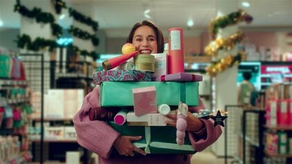 Vrouw die kerstcadeaus vasthoud in een etos winkel