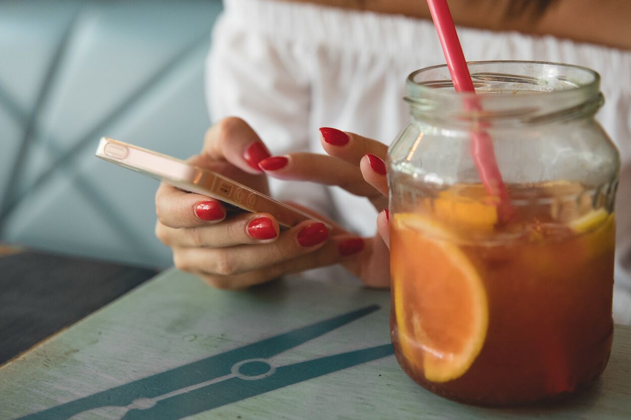 vrouwenhanden met rode gelakte nagels en een drankje