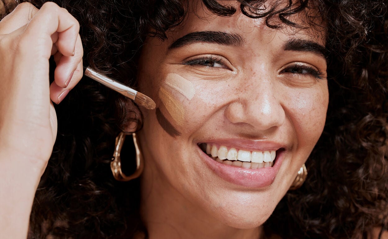Vrouw die BB cream, CC cream en foundation in verschillende kleuren aanbrengt op haar gezicht.