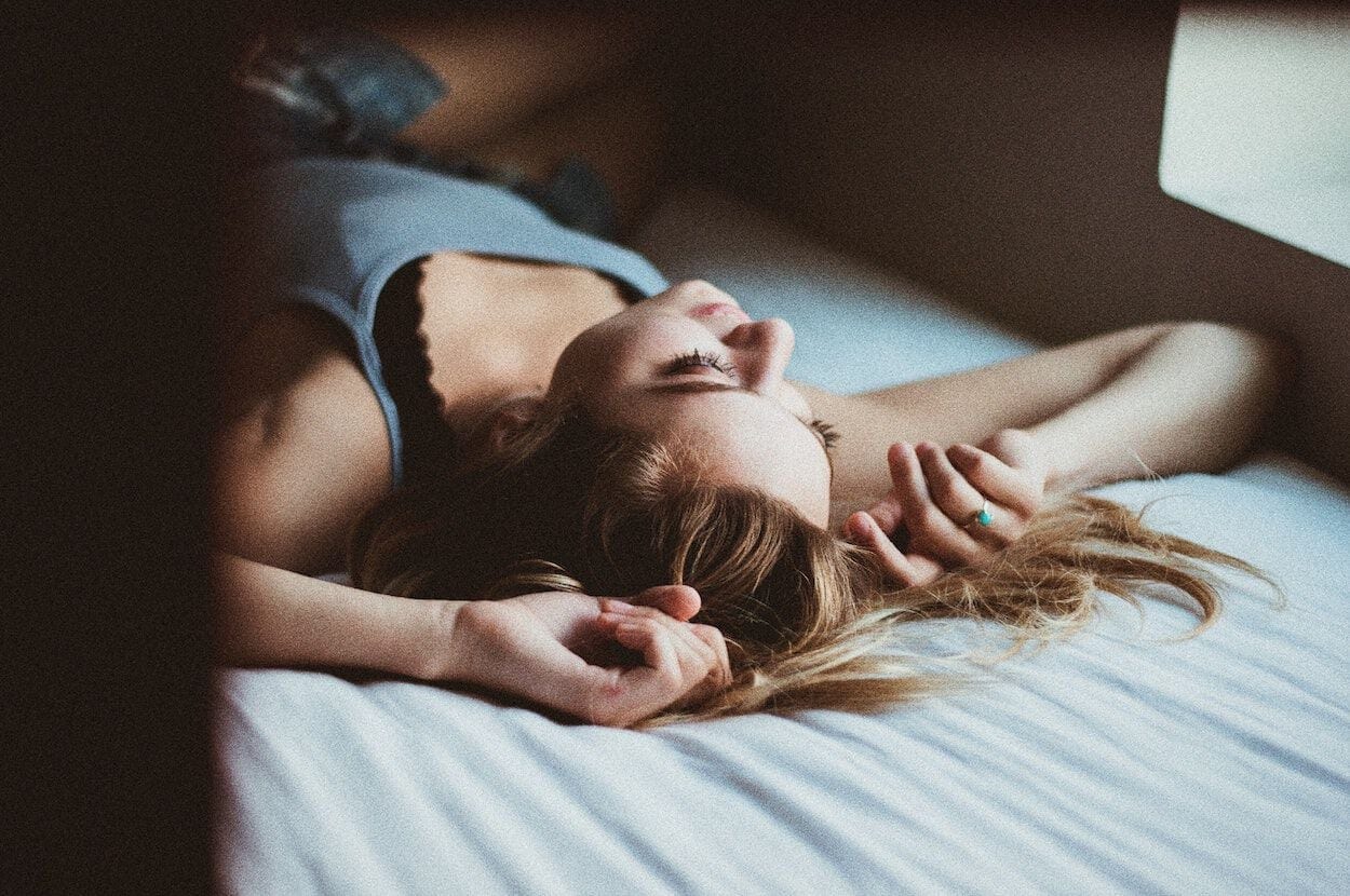 Vrouw die op bed ligt. Ze zit midden in haar menstruatie