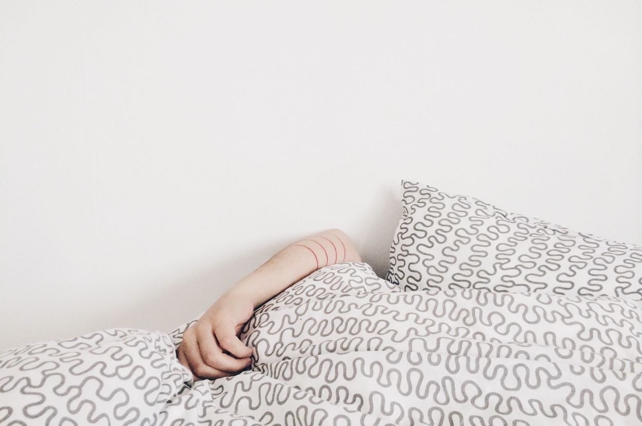 arm in bed onder dekens