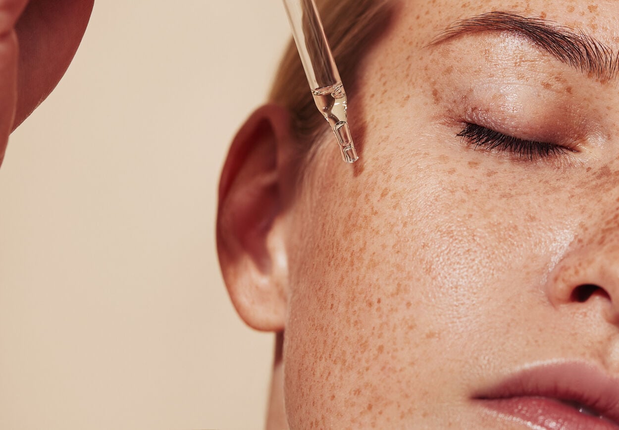 Vrouw die een serum met peptides op haar huid aanbrengt als onderdeel van haar gezichtsverzorgingsroutine.