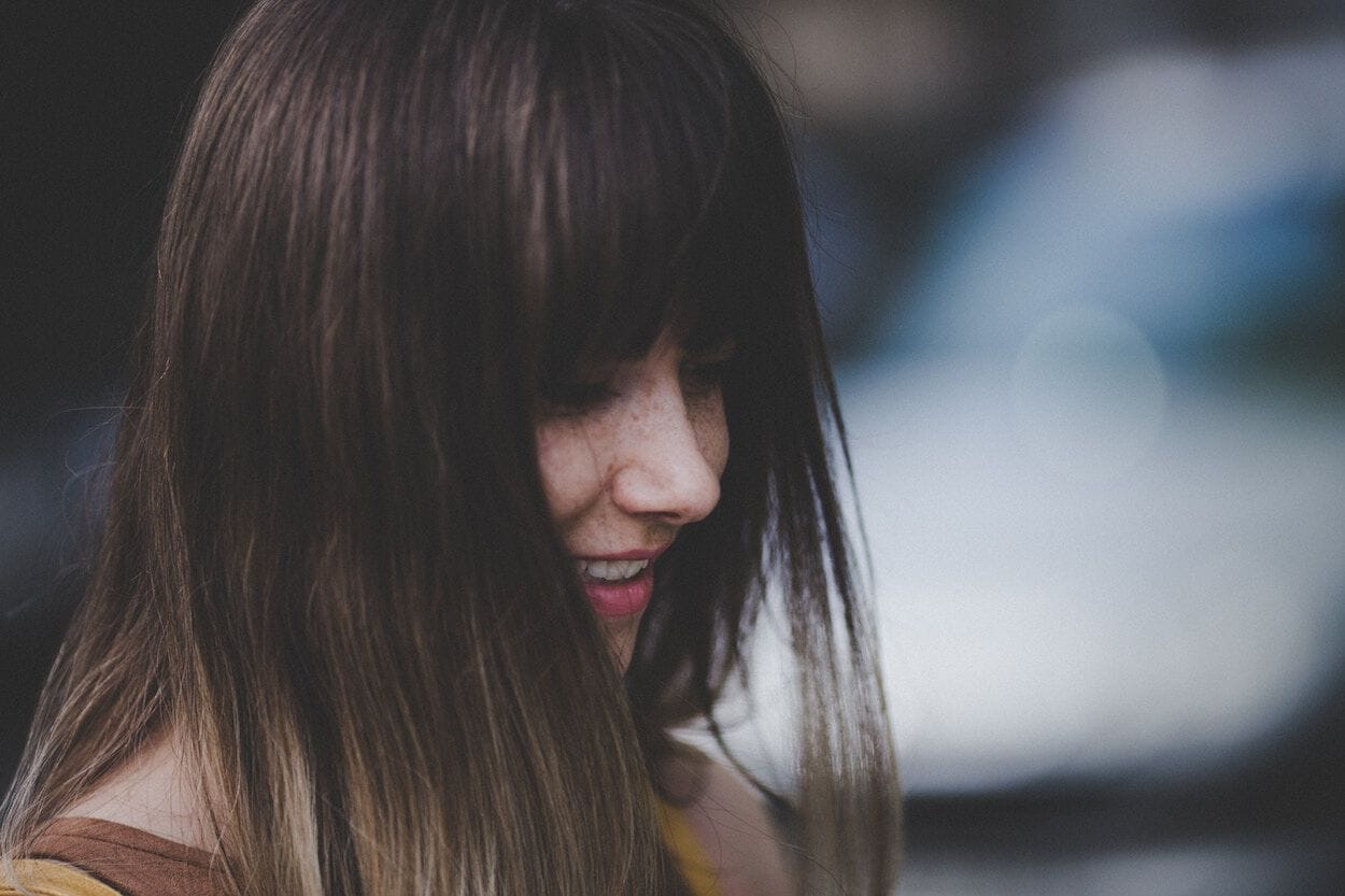 vrouw met donker haar die naar beneden kijkt en lacht