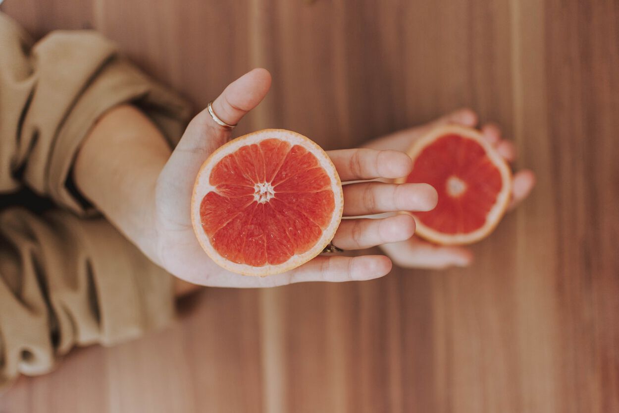 vrouw houdt een grapefruit schijfje vast