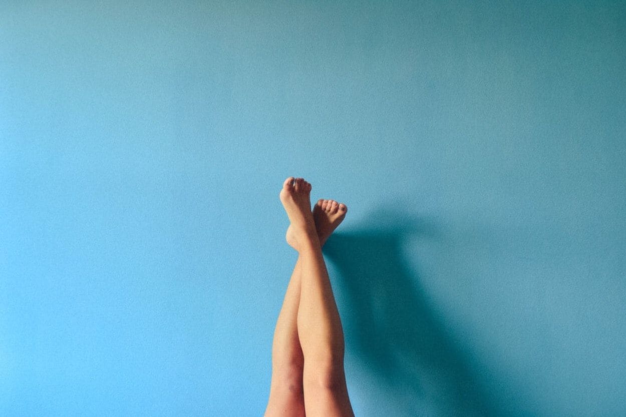 vrouw met blote benen in de lucht tegen een blauwe muur
