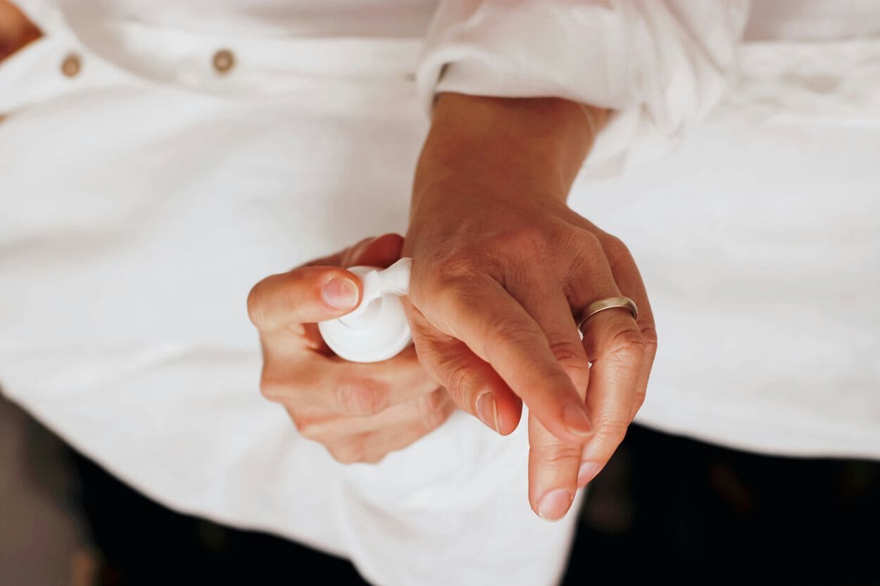 Vrouw die met een pompje een crème op haar linkerhand doet