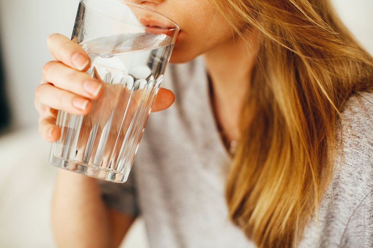 Een vrouw met een droge mond drinkt een glas water
