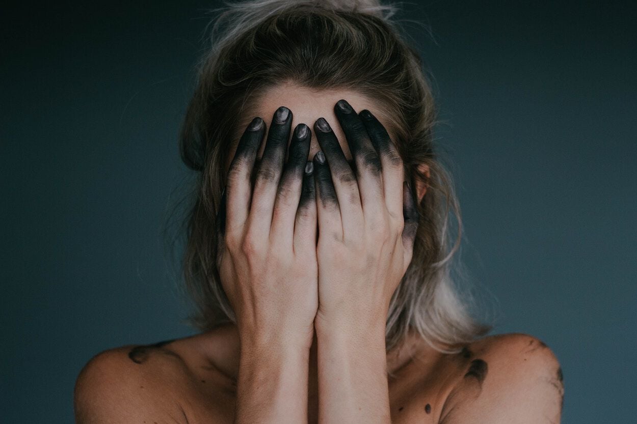 vrouw met handen voor ogen met houtskool op haar handen