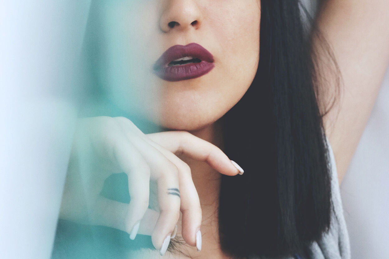 Vrouw met paarse lippenstift en haar hand onder haar kin