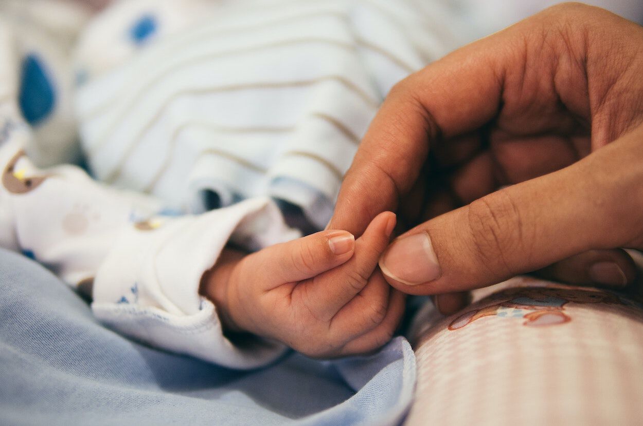 moeder houdt het handje van haar baby vast