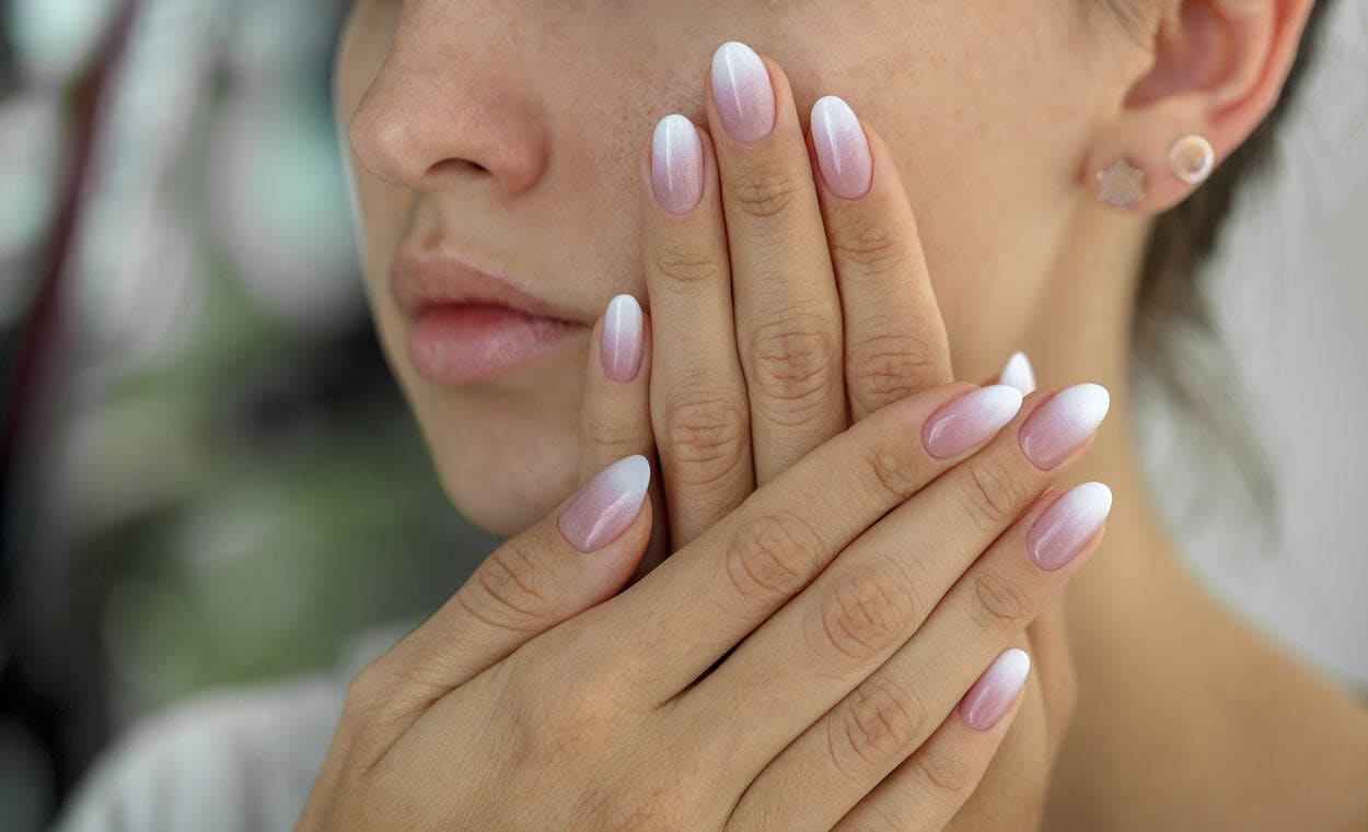 Vrouw dmet babyboom nagels met witte en roze nagellak.