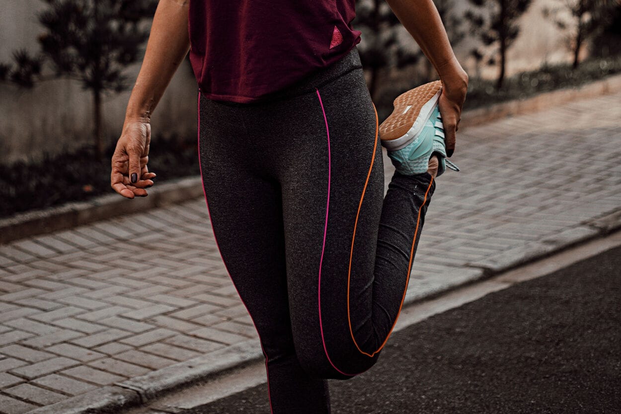 vrouw in sportkleding is haar been aan het strekken
