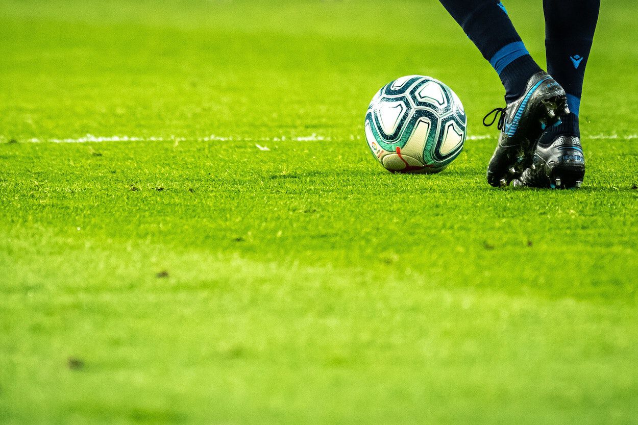 Voetbalveld met een voetbal en schoenen