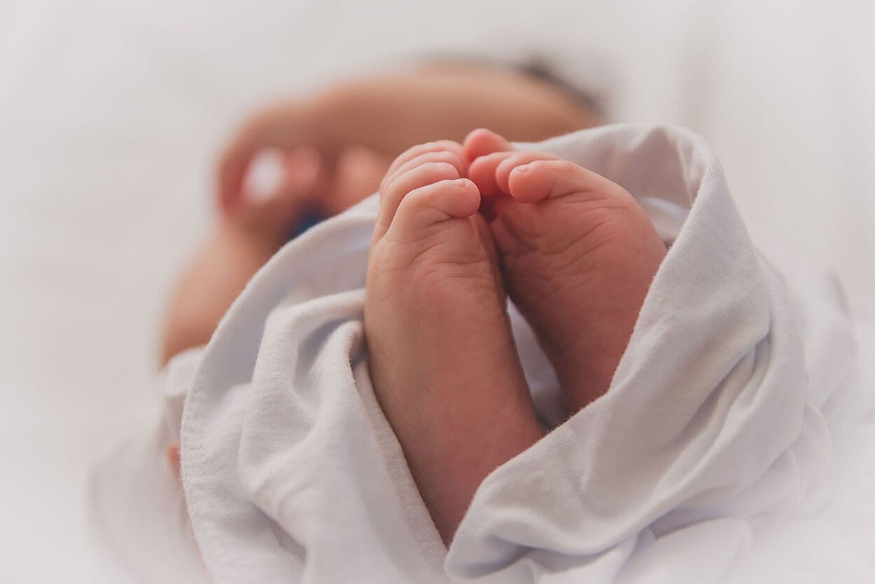 Babvoetjes die tegen elkaar aanzitten met een wit deken er omheen