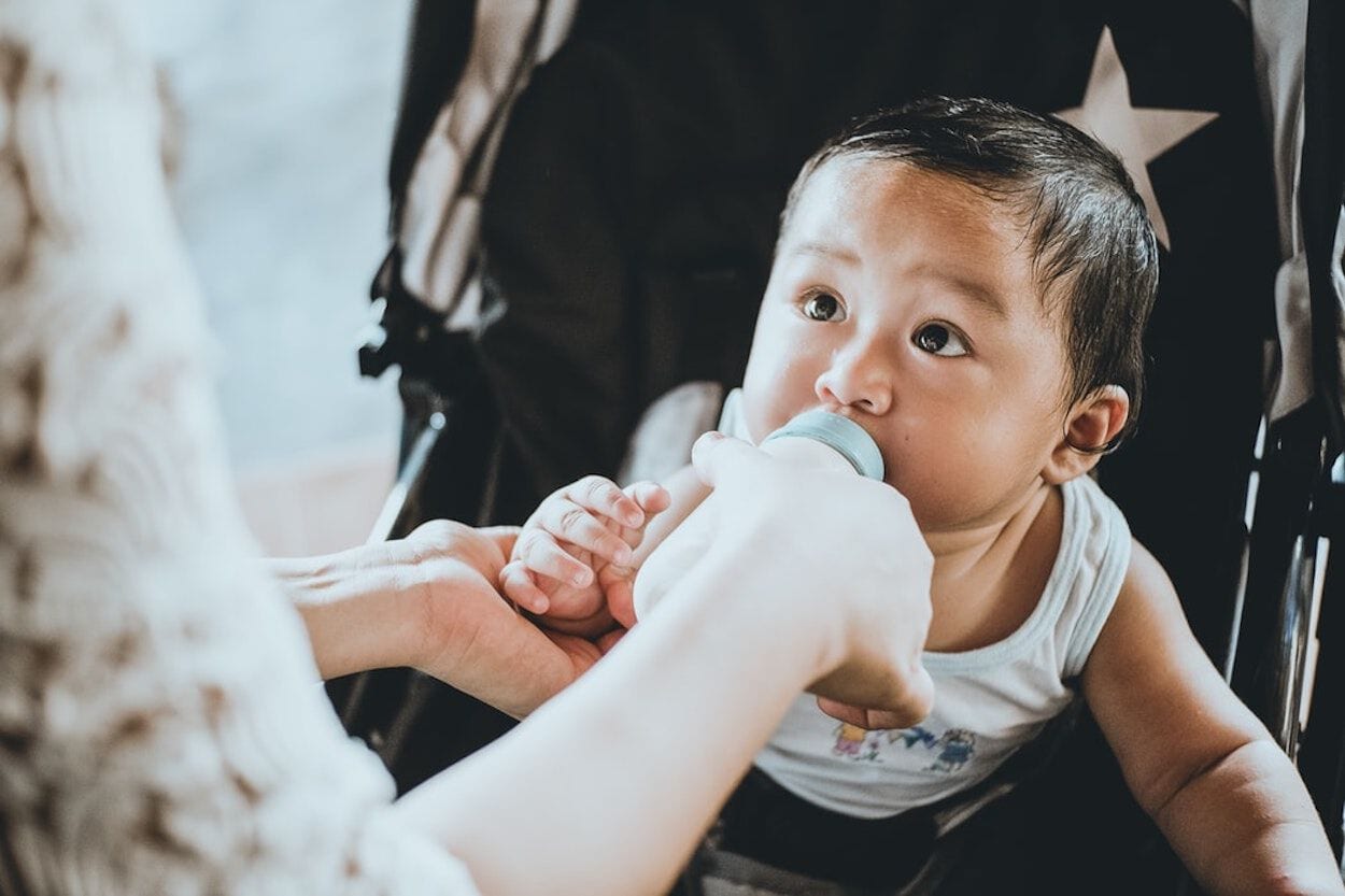 kindje drinkt flesvoeding in kinderwagen