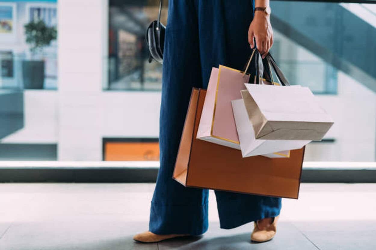 Persoon die tasjes draagt wat refereert naar een koopverslaving waarbij iemand veel geshopt heeft