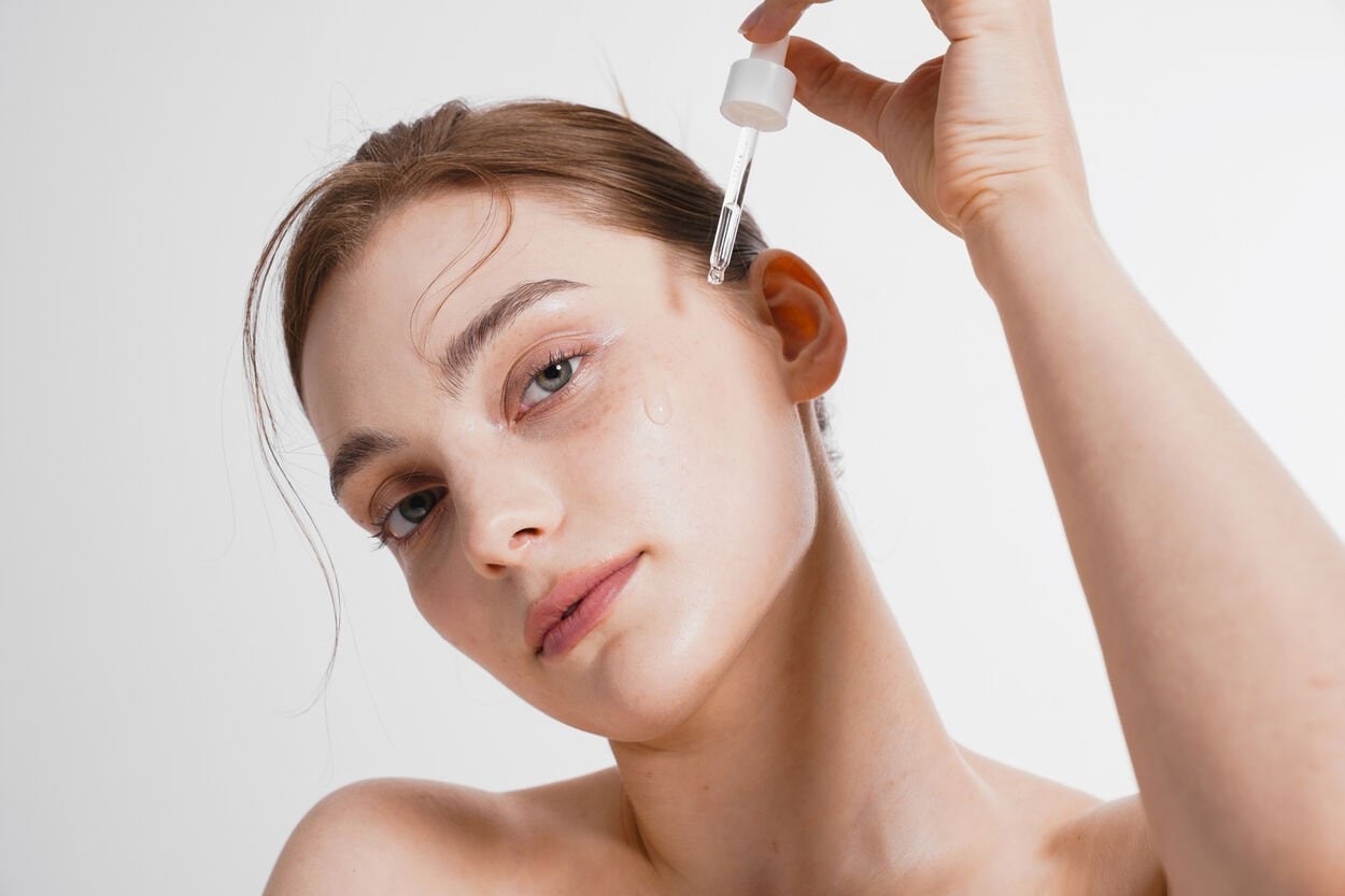 Vrouw die serum Q10 op haar gezicht aanbrengt.