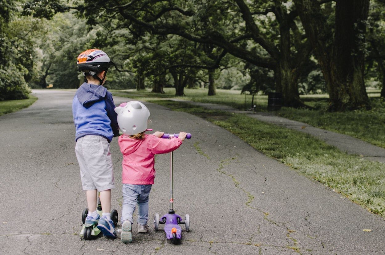 twee kinderen op een step met helm