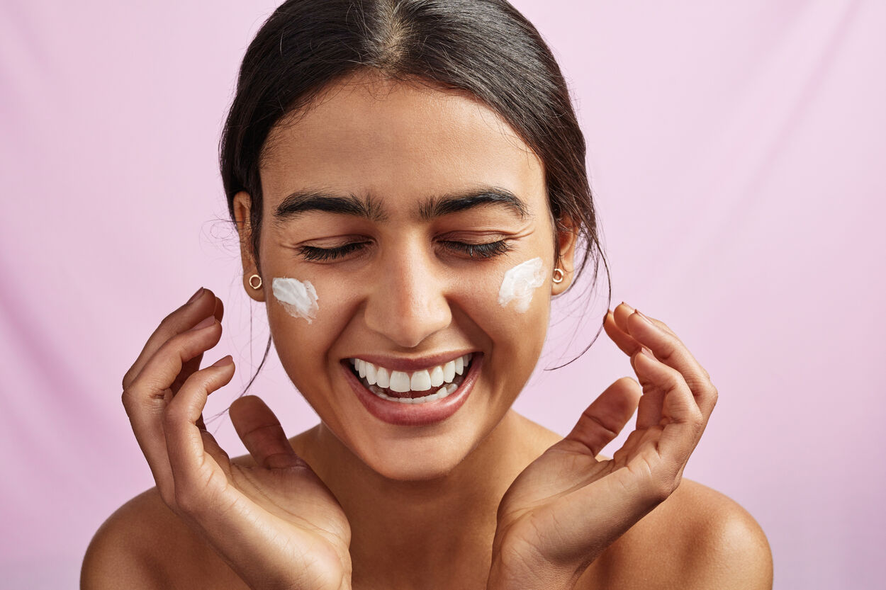 Vrouw die een dagcrème met retinol op haar gezicht aanbrengt.