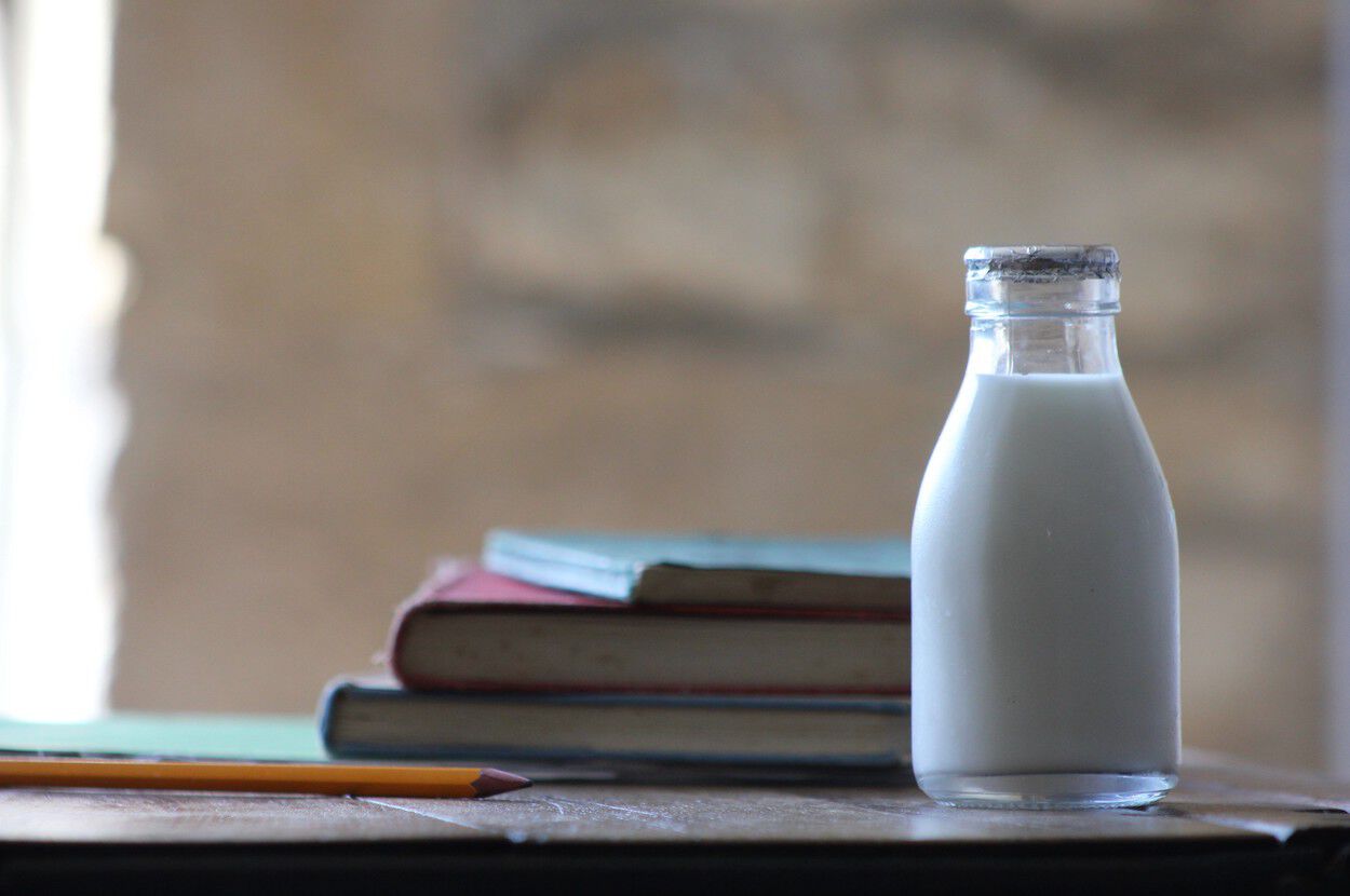 flesje melk op tafel naast boeken