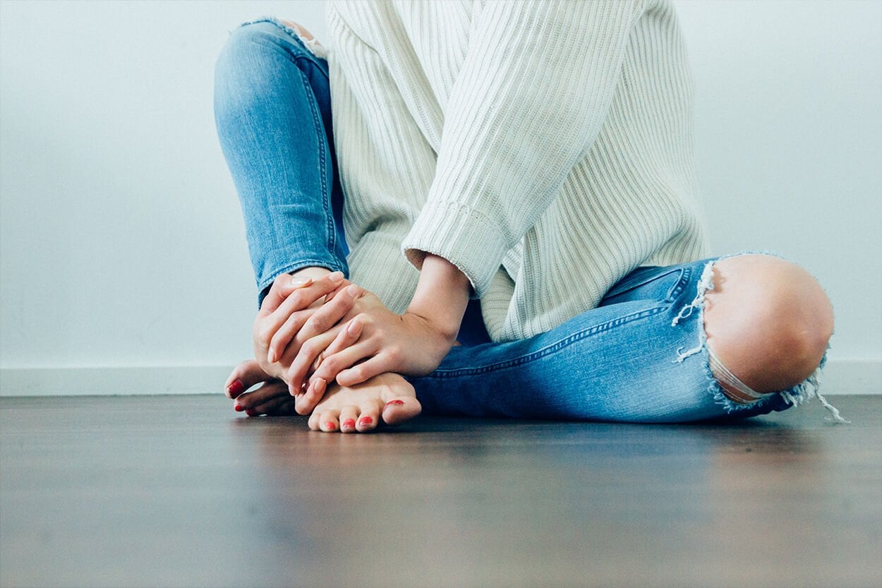 vrouw zit met gekruiste benen en blote voeten op de grond