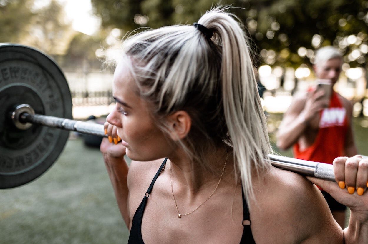 vrouw doet squat met gewicht op haar nek