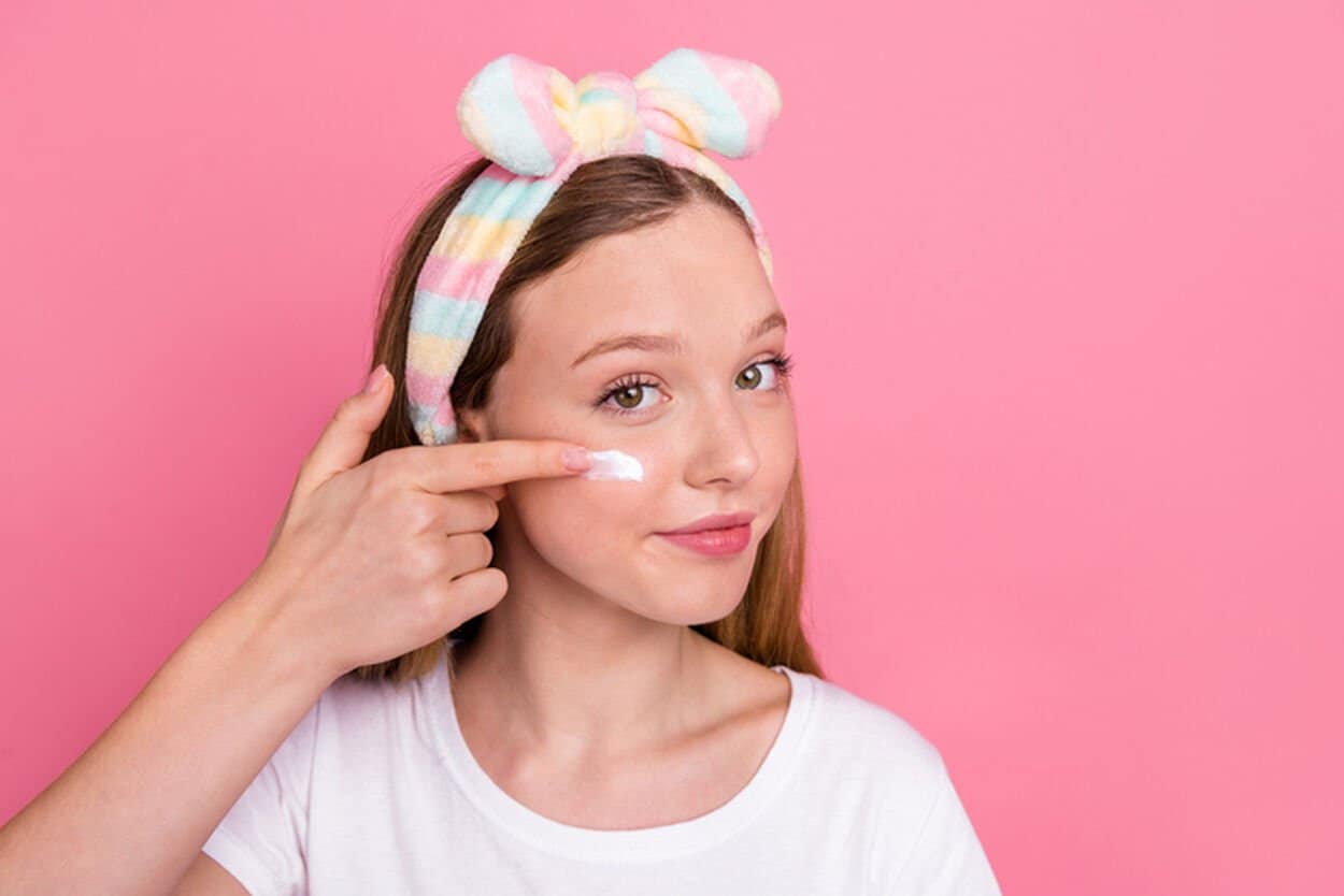 Tiener die skincare op haar jonge huid aanbrengt.