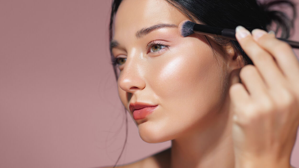 Vrouw die highlighter aanbrengt met een make-upkwast.