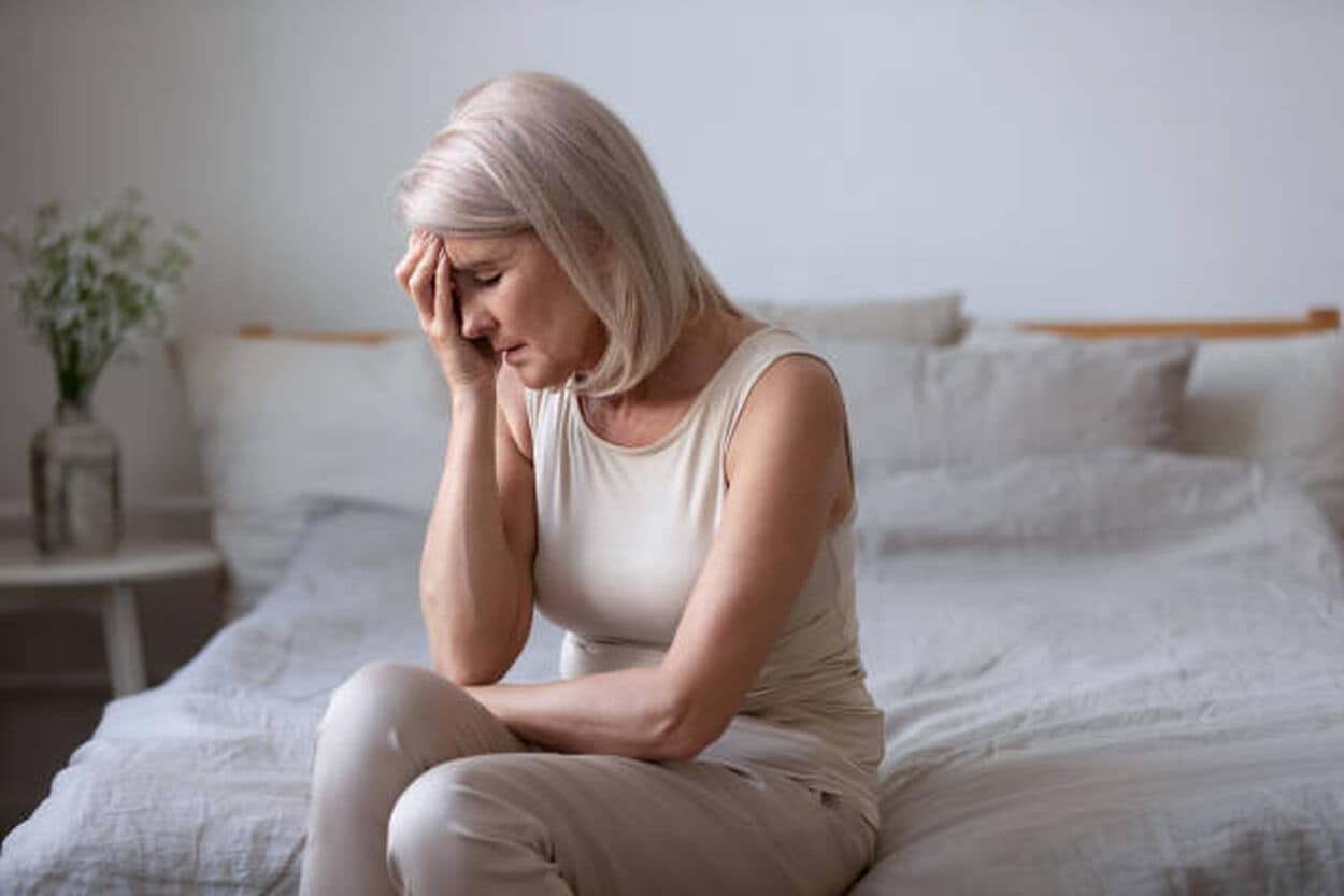 Vrouw die op bed zit met clusterhoofdpijn
