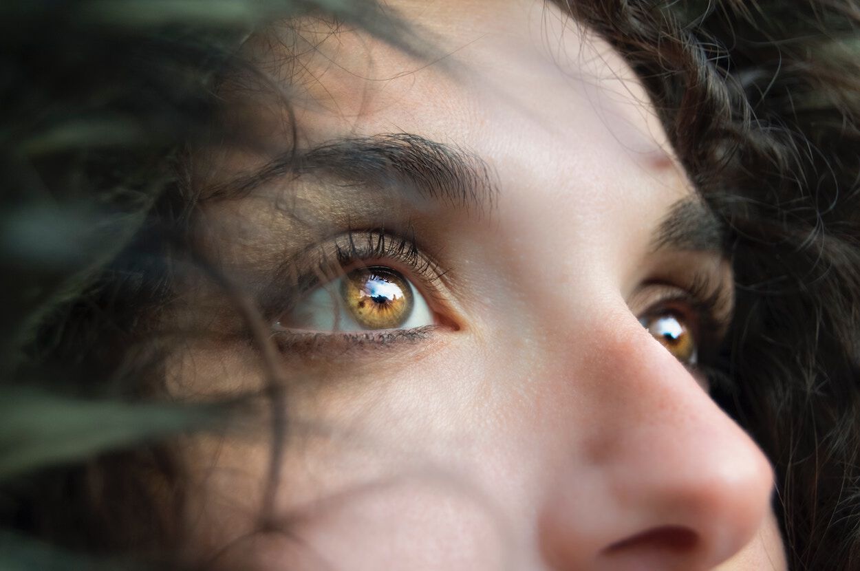 vrouw met donker haar kijkt in de verte