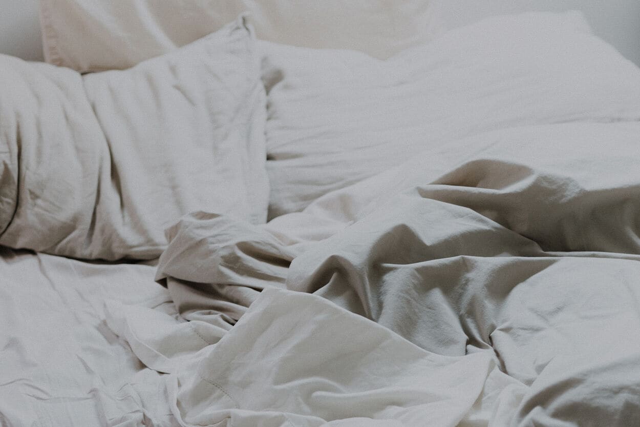 bed met witte kussens en laken