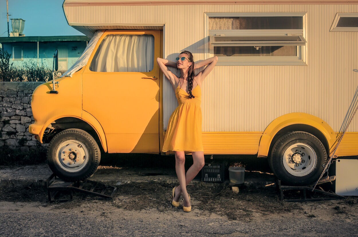 vrouw voor gele camper vakantie