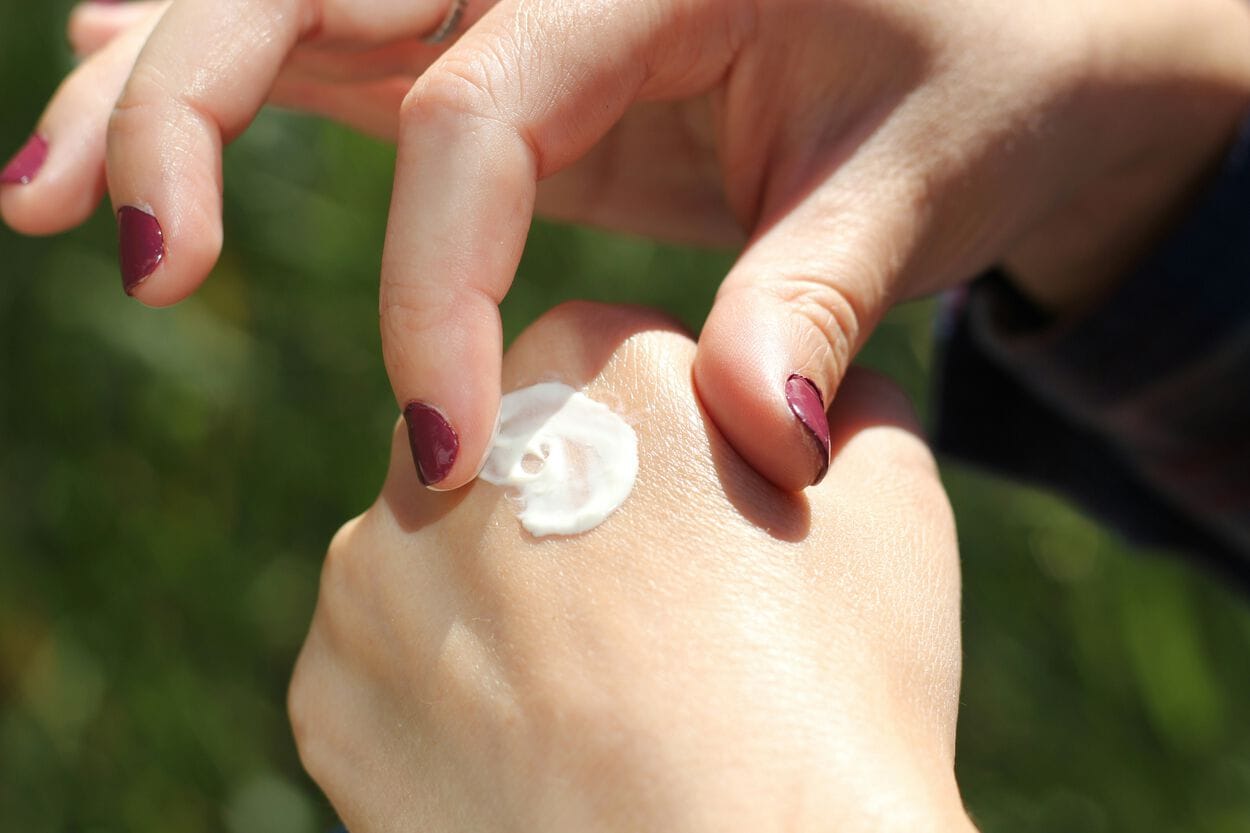 Vrouw die een beetje witte crème op haar linkherhand heeft