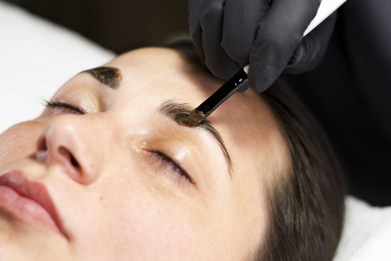 Vrouw die haar wenkbrauwen laat verven. De kleur van de wenkbrauwverf is te donker uitgevallen en ze wil de wenkbrauwverf verwijderen.