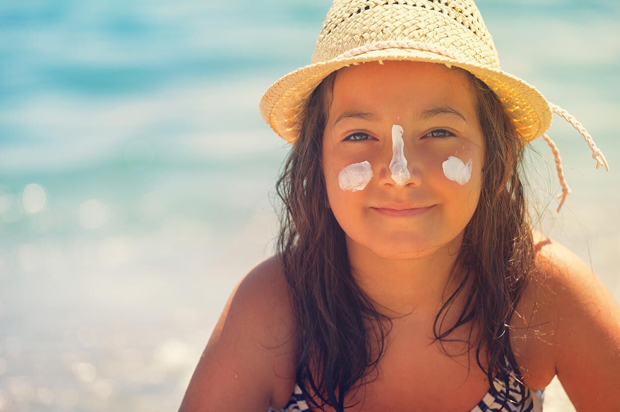 meisje met strandhoed en zonnebrand vlekken op haar hoofd