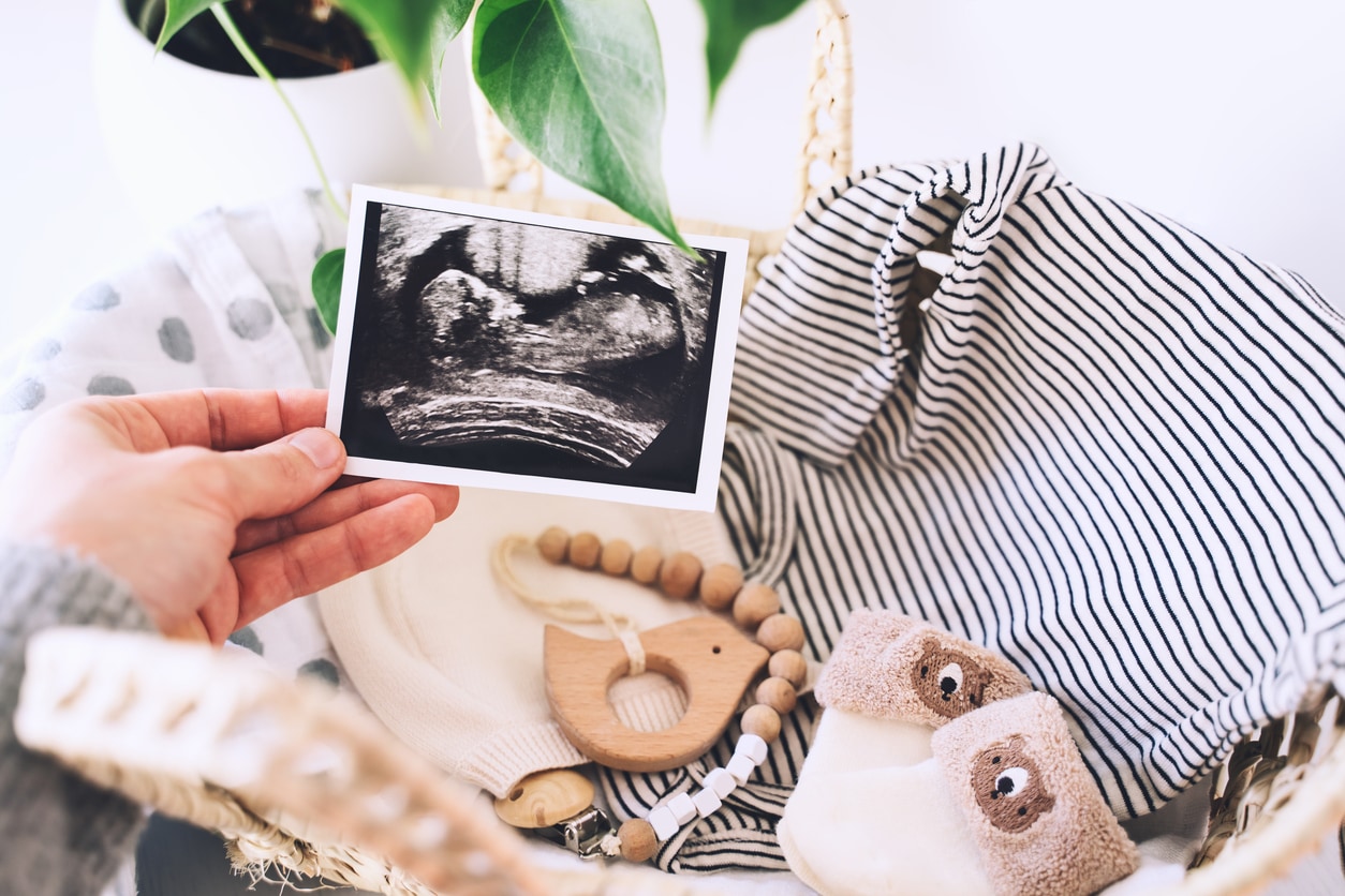 hand met echo en babykleertjes en babyspeelgoed