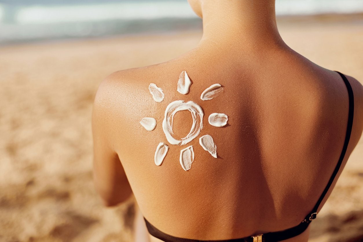Vrouw op strand met zonnebrand als zon op haar rug